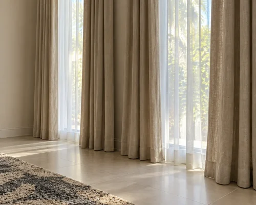 Side view of eyelet linen curtains on a champagne-bronze double rod in a Maple 3 villa living room